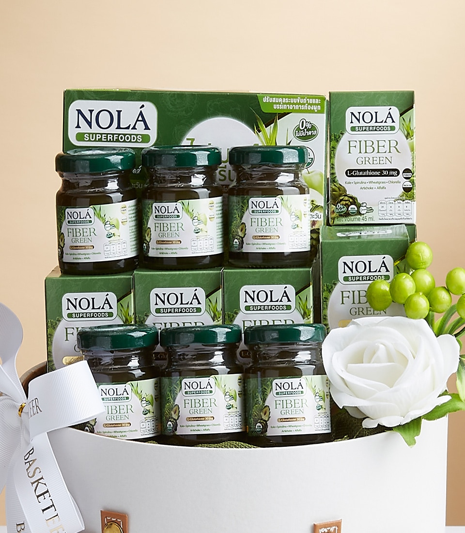 A luxurious display showcasing exquisite 30 ml bottles and boxes of Nola Superfoods Fiber Green Glutathione. Set against a pristine white backdrop, the arrangement is accentuated by a sophisticated white decorative bow and an elegant artificial flower. The premium packaging, in refreshing green and white, prominently features detailed product information. A beautiful box adorned with the prestigious 'Basketeer' logo adds a touch of opulence to this inviting scene.