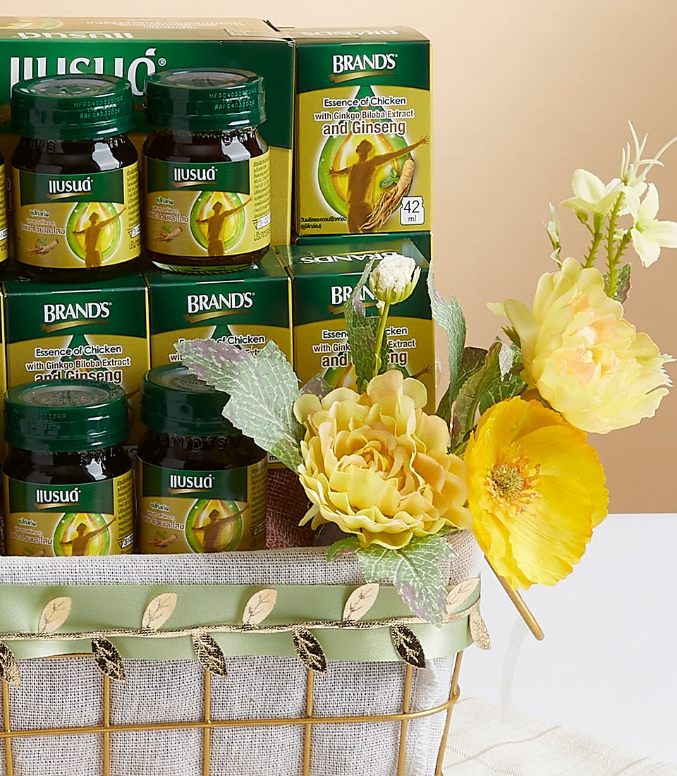 An exquisite gift basket showcasing an array of Ilusat Essence of Chicken with Cordyceps and Ginseng. The luxurious presentation is elevated with a beautiful green ribbon and opulent blooms in shades of green and yellow. The sophisticated arrangement is complemented by the Basketeer logo elegantly displayed on select boxes, making it a distinguished choice for the discerning connoisseur.