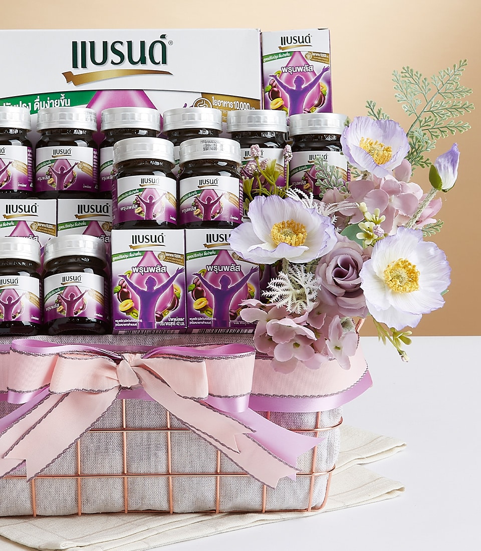 A lavishly arranged gift basket featuring an exquisite selection of premium supplements, delicately nestled among vibrant purple and pristine white flowers. The basket is adorned with a sumptuous pink ribbon and bow, prominently displaying the Basketeer logo for an added touch of elegance. Set against a soft beige backdrop, this luxurious presentation captivates with its colorful and refined display, inviting you to indulge in the ultimate gifting experience from Basketeer.
