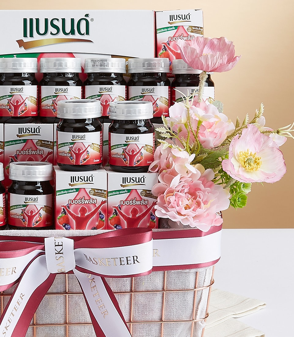 An opulent gift basket crafted by Basketeer, elegantly showcasing a tiered arrangement of exquisite jars of strawberry jam. Each jar is meticulously placed, surrounded by delicate pink and white blossoms that exude sophistication. The basket is adorned with a luxurious white ribbon, adorned with 