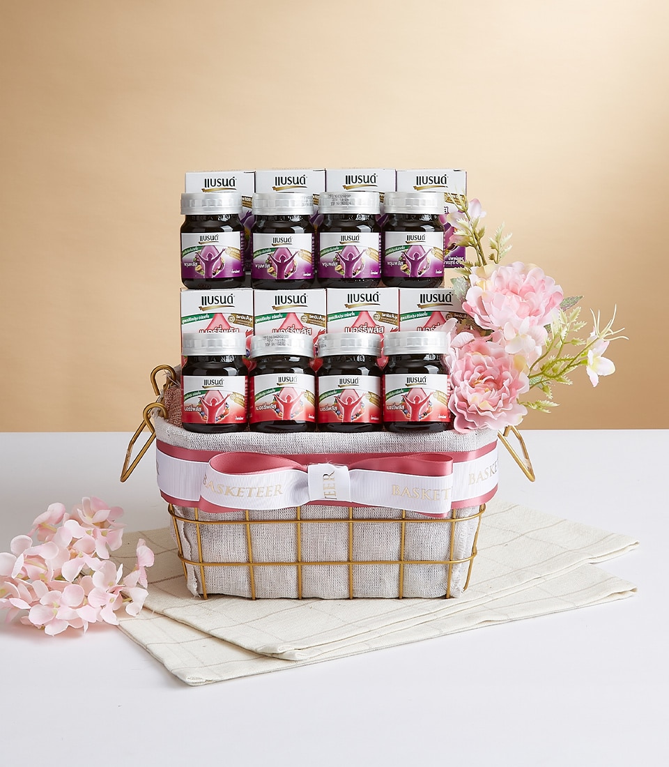 A luxurious gift basket showcasing 12 exquisite jars of Ilusso fruit spreads, meticulously arranged in three elegant rows. The basket exudes opulence with delicate pink flowers and is beautifully finished with a sumptuous pink ribbon featuring the distinguished 