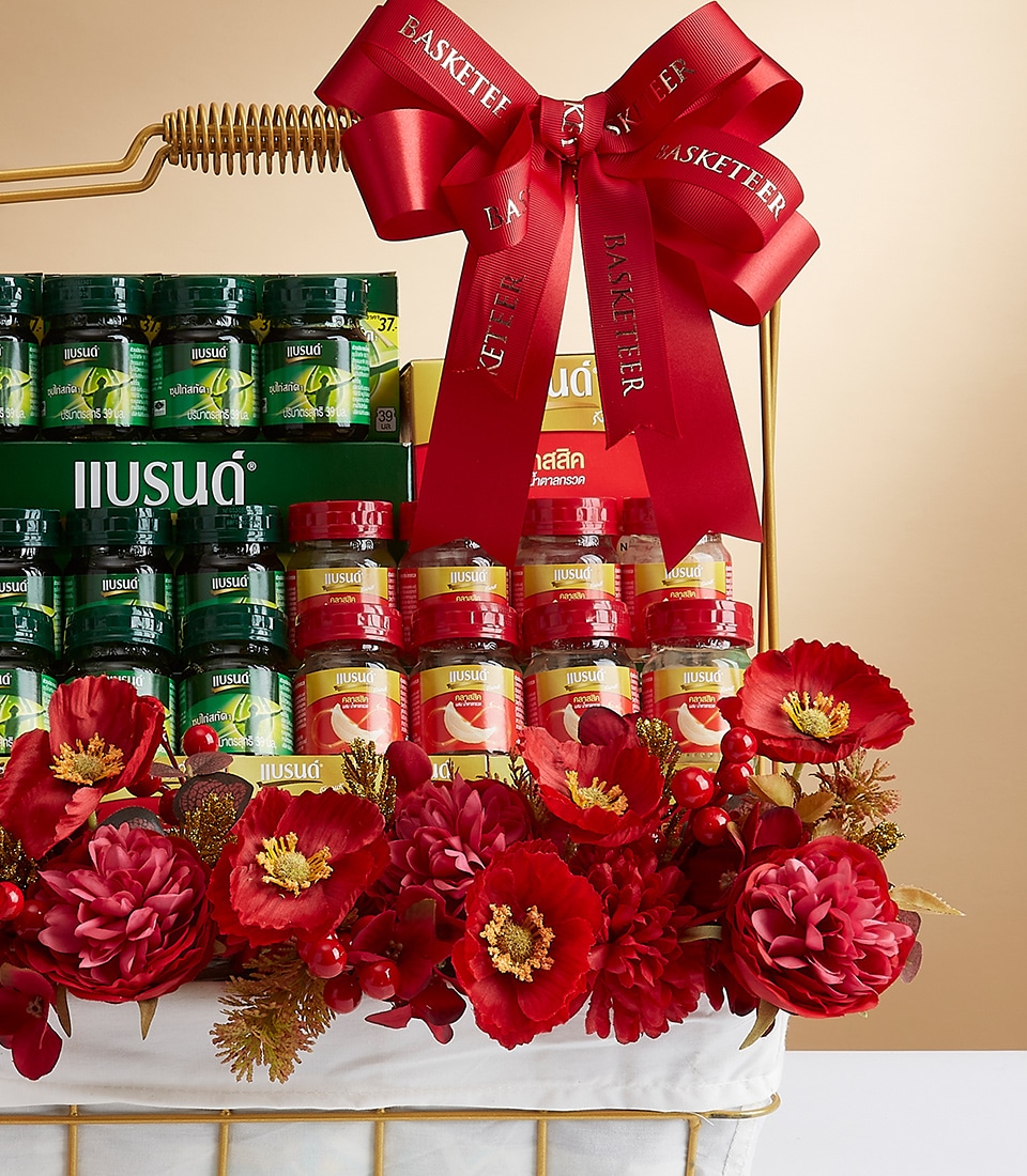 A luxurious gold basket brimming with an exquisite selection of health supplements elegantly wrapped in rich red and golden-yellow labels. The basket is adorned with a magnificent, oversized red ribbon bow, intricately tied to perfection. An array of vibrant red flowers adds an opulent touch, enhancing the allure of the arrangement. The distinguished ribbon bears the 