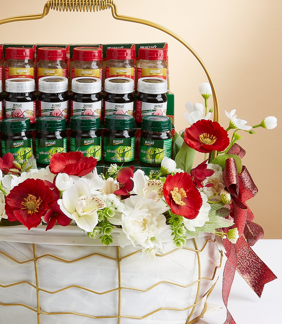 A tasteful, decorative basket embellished with vibrant red and pristine white flowers, elegantly showcasing an exquisite assortment of premium spice jars, including aromatic coriander and rich cumin. Each jar is meticulously arranged in perfect rows within the basket, which features a luxurious gold-colored handle. A sophisticated red ribbon bearing the Basketeer logo graces the arrangement, infusing it with a festive yet refined touch.