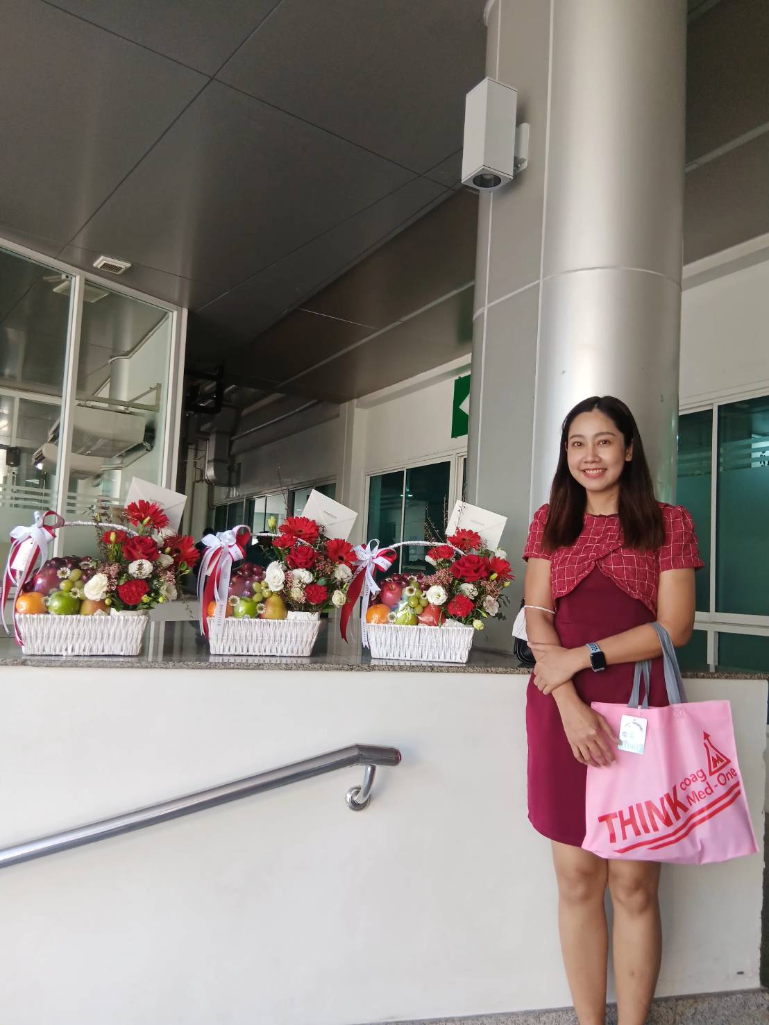 Elegant fruit gift baskets with red flowers and ribbons in white woven baskets, arranged for corporate gifting or festive occasions.