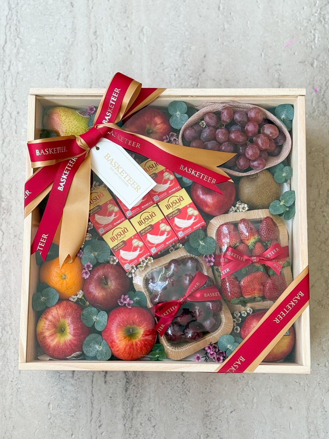 Luxurious fresh fruit hamper featuring apples, pears, grapes, strawberries, chocolates and juice, elegantly wrapped by Basketeer Bangkok.
