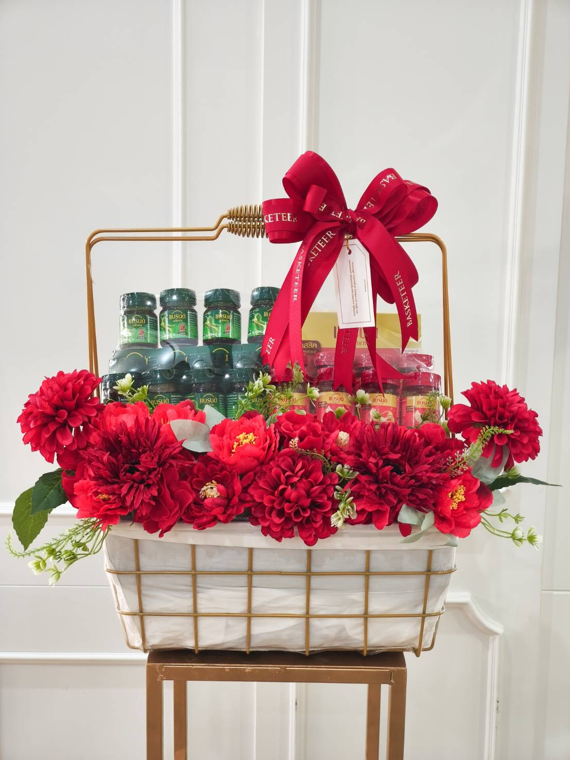 Luxury health gift basket filled with premium supplements and decorated with large red flowers and a red satin ribbon.