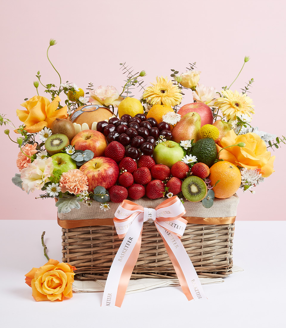 Mixed Fresh Fruits With Yellow Tone Flowers Gift In The Basket With a Bow
