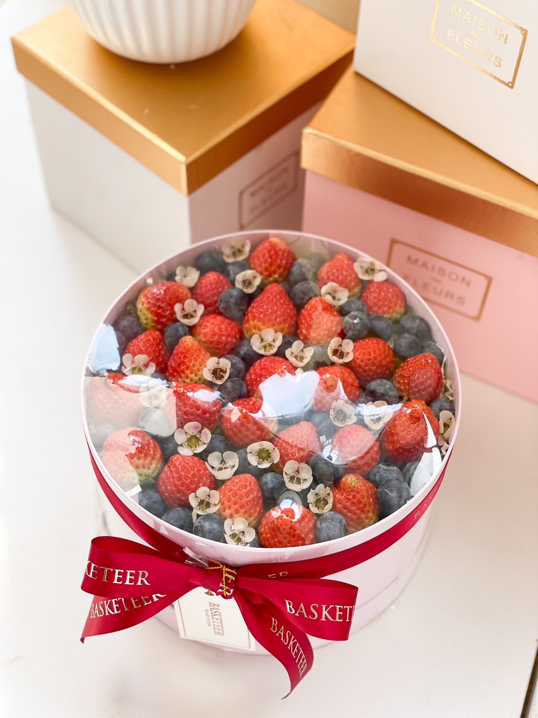 A luxurious berry gift box filled with fresh strawberries, blueberries, and edible flowers, elegantly presented with a red ribbon—perfect for healthy gourmet gifting.