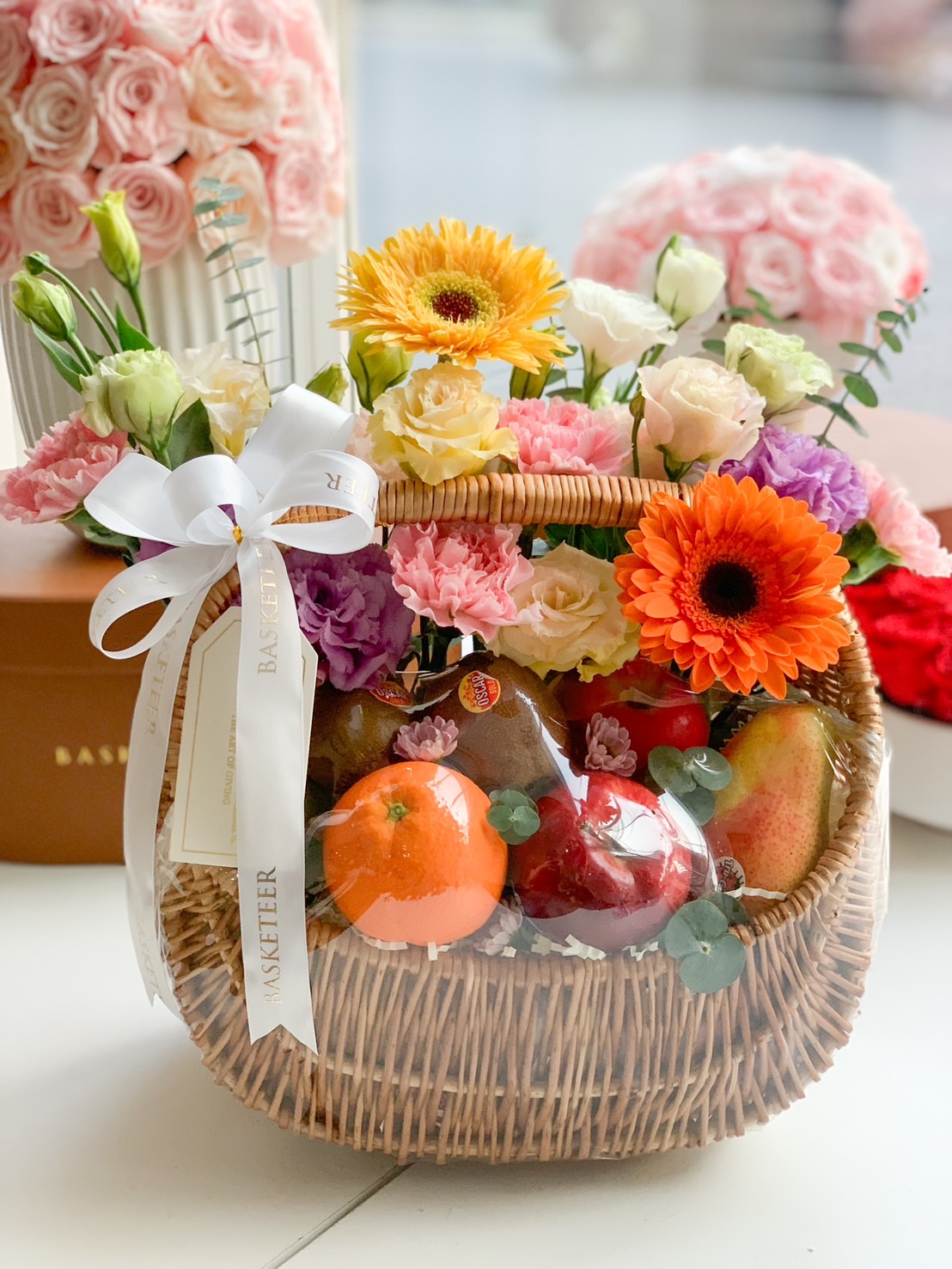 A beautifully handcrafted fruit and flower gift basket, filled with premium fresh fruits like apples, oranges, and pears, accented with colorful seasonal blooms—perfect for celebrations and special occasions.