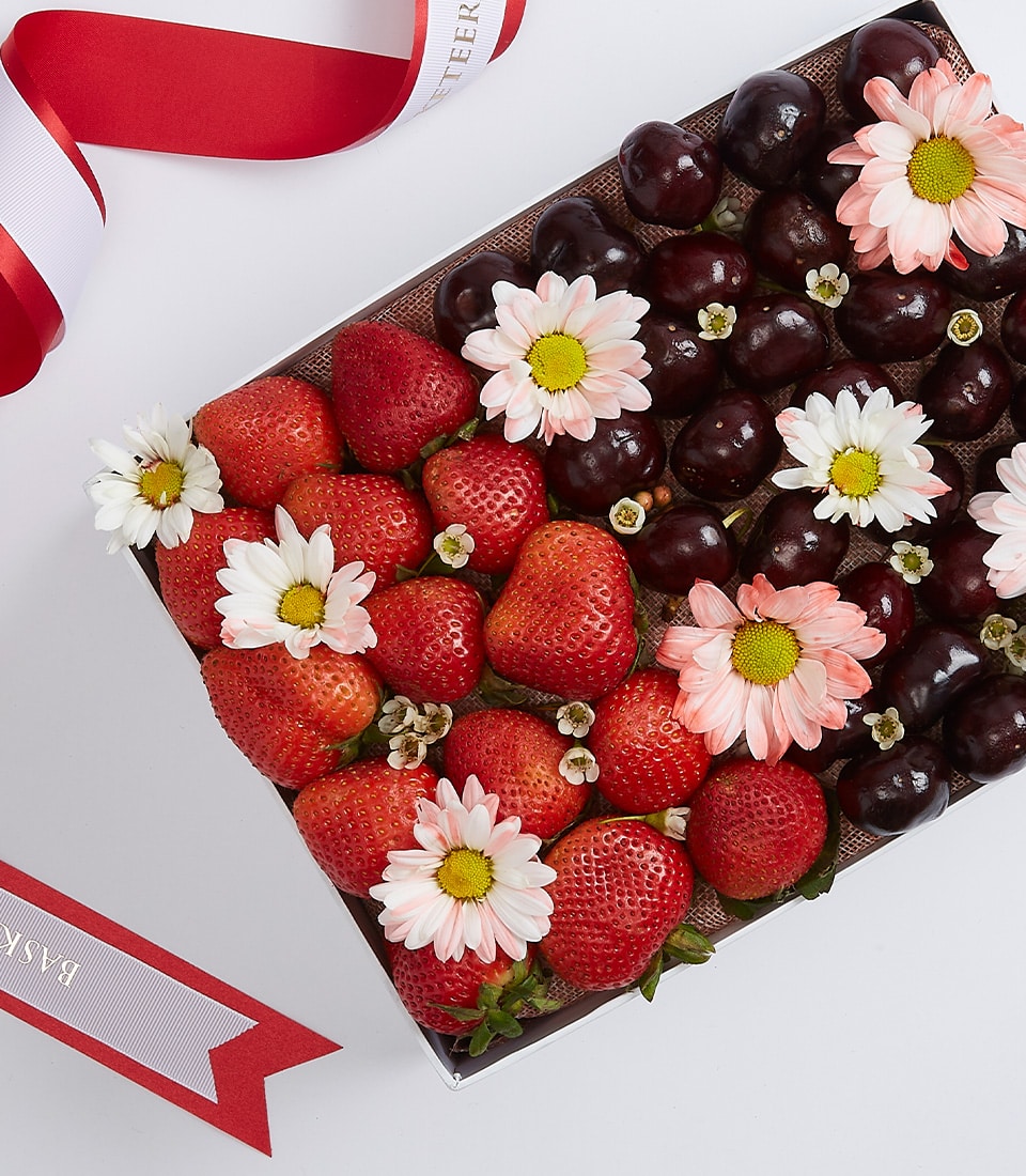 A lavish rectangular box brimming with succulent fresh strawberries and luscious dark cherries, elegantly labeled as the 