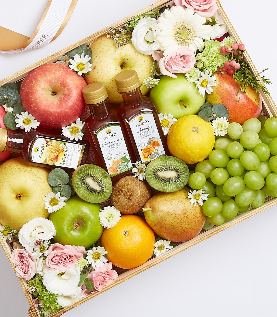 Indulge in the epitome of elegance with Basketeer’s Fresh Fruit Gift Box, a luxurious wooden crate exquisitely packed with an assortment of succulent fruits and delicate flowers. This beautifully crafted box showcases crisp apples, luscious pears, zesty lemons, exotic kiwis, and juicy green grapes. Complementing these fresh delights are two jars of golden honey and two charming bottles of cider. Nestled among the vibrant fruits are breathtaking pink and white flowers intertwined with dainty white daisies, creating a sumptuous visual feast. Adorned with a ribbon proudly displaying the Basketeer logo, this gift box embodies opulence and invites you to savor each moment of its captivating charm.