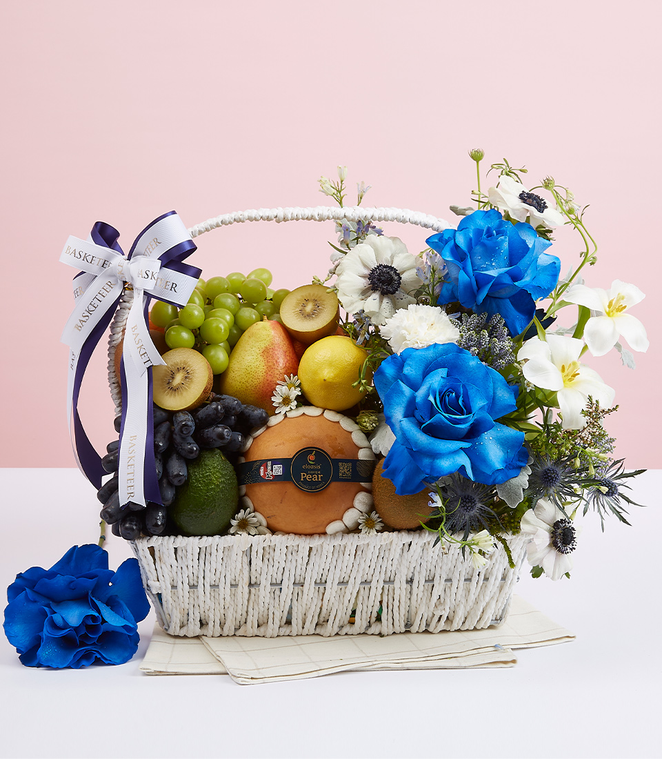 White gift basket with handle The basket is filled with a variety of fresh fruits such as green grapes, apples, avocados and many other healthy fruits. Decorated with fresh white flowers and beautiful blue and tied with a bow Blue and white ribbon with the words 