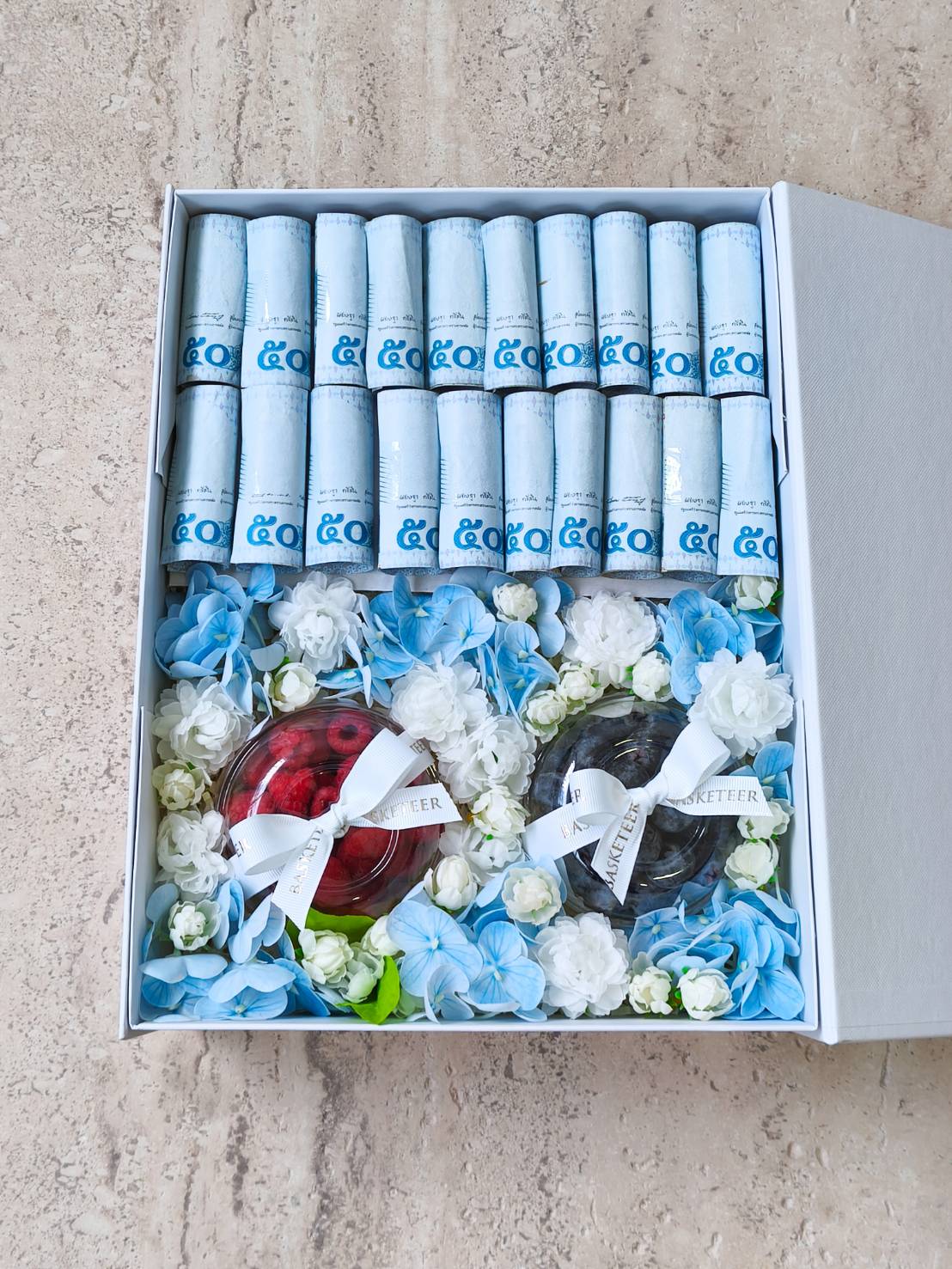 Luxury cash gift box with 50-baht banknotes, two premium jelly desserts, and fresh blue and white floral decorations.