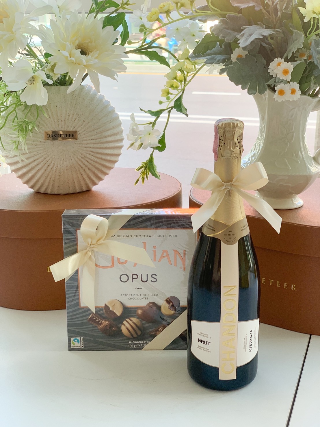 Chandon Brut sparkling wine bottle with Guylian Opus assorted Belgian chocolates gift set tied with cream ribbons.