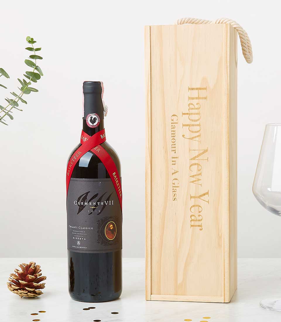 A sumptuous bottle of Chianti Classico wine adorned with a crimson Basketeer ribbon rests gracefully beside an elegant wooden gift box featuring the inscription 