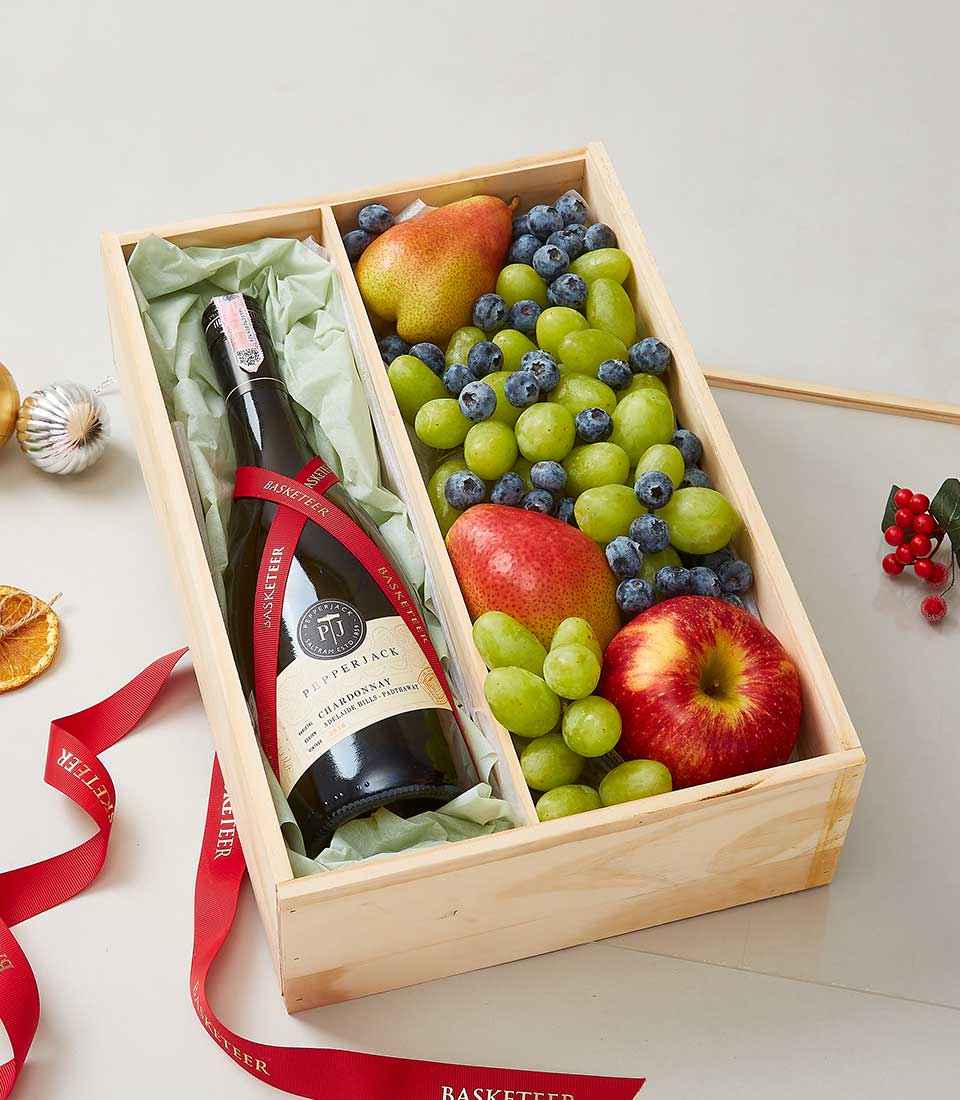 A luxurious wooden gift box from Basketeer featuring an exquisite bottle of Pepperjack wine, nestled among a vibrant assortment of fresh grapes, succulent blueberries, crisp apples, and a perfectly ripe pear. The scene is elegantly adorned with a rich red ribbon bearing the distinguished 