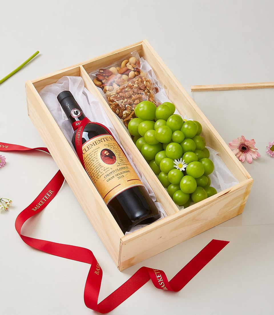 Chianti Wine & Nut Gift Box with Clemente VII bottle, fresh green grapes, and assorted nuts, arranged in a wooden box with a red ribbon.