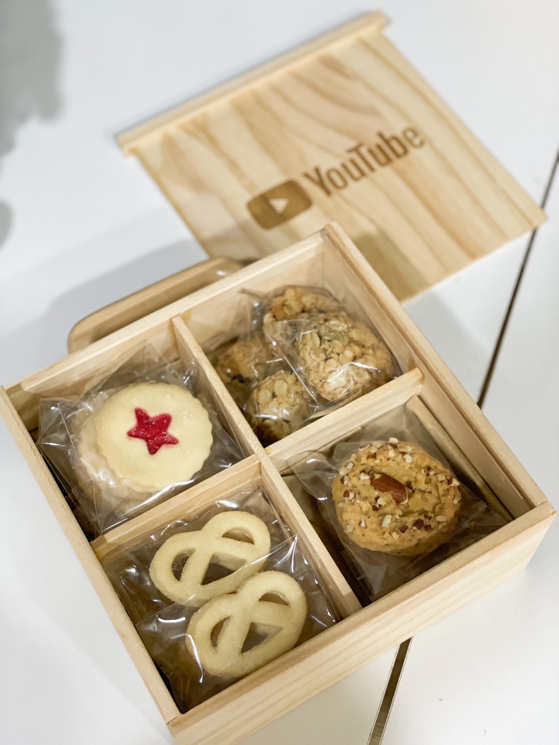 Wooden gift box with assorted premium cookies, including butter pretzels, jam-filled cookies, and nutty treats by Basketeer.