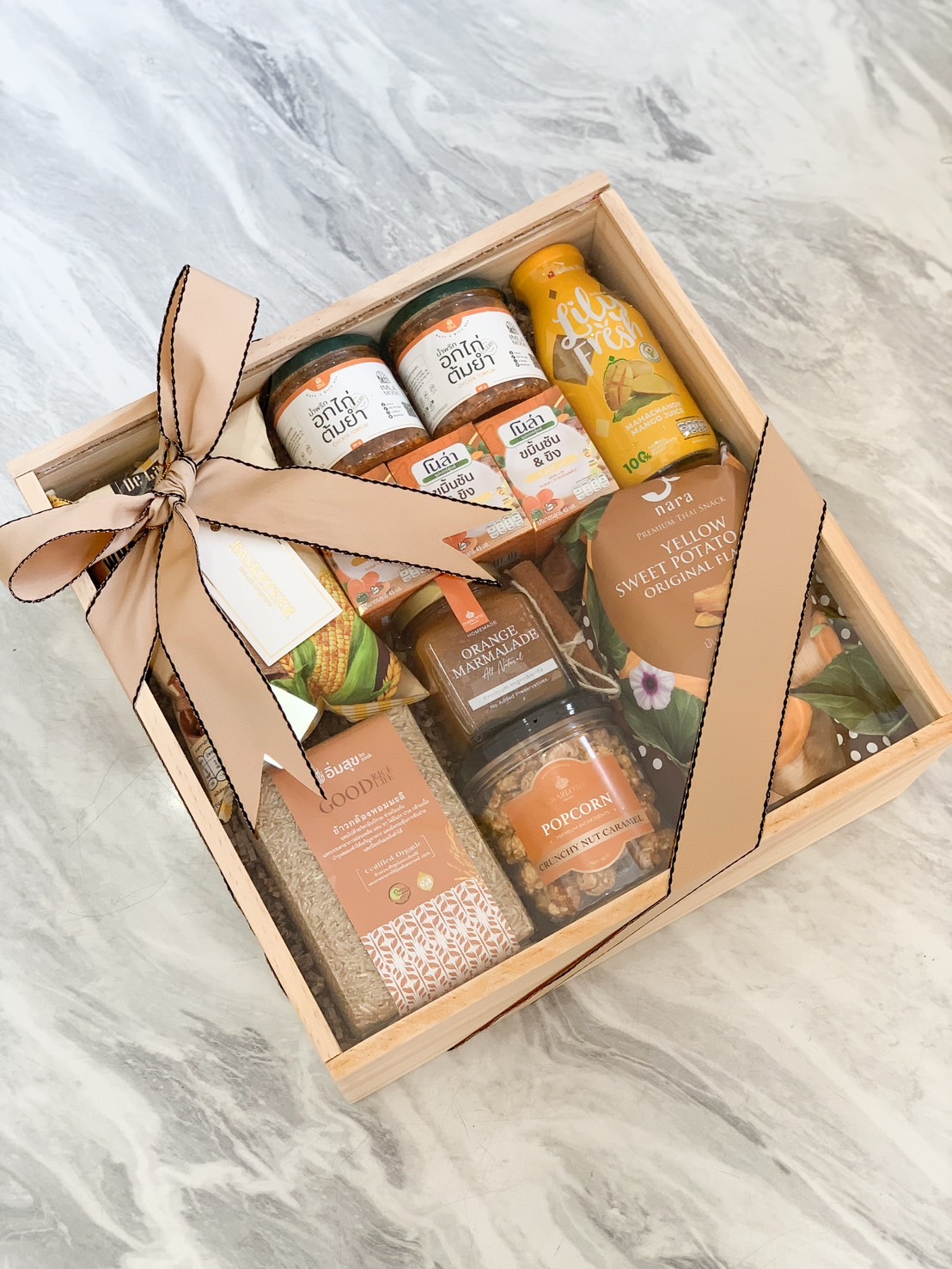 Wooden gift box with organic rice, fruit juices, caramel popcorn, and gourmet snacks by Basketeer.