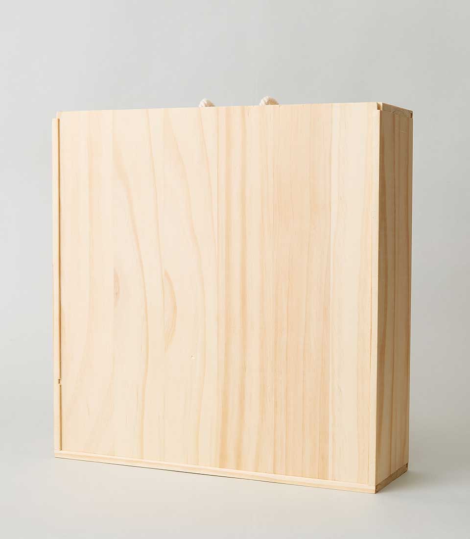 A luxurious Basketeer wooden gift box is showcased against a pristine white background. Crafted from light, refined wood, the rectangular box exudes elegance with its smooth surface and minimalist, clean lines. Adorned with two petite rope handles at the top for effortless carrying, the box epitomizes sophistication and invites you to discover its exquisite contents. A subtle yet polished Basketeer logo on the side hints at the curated luxury within.