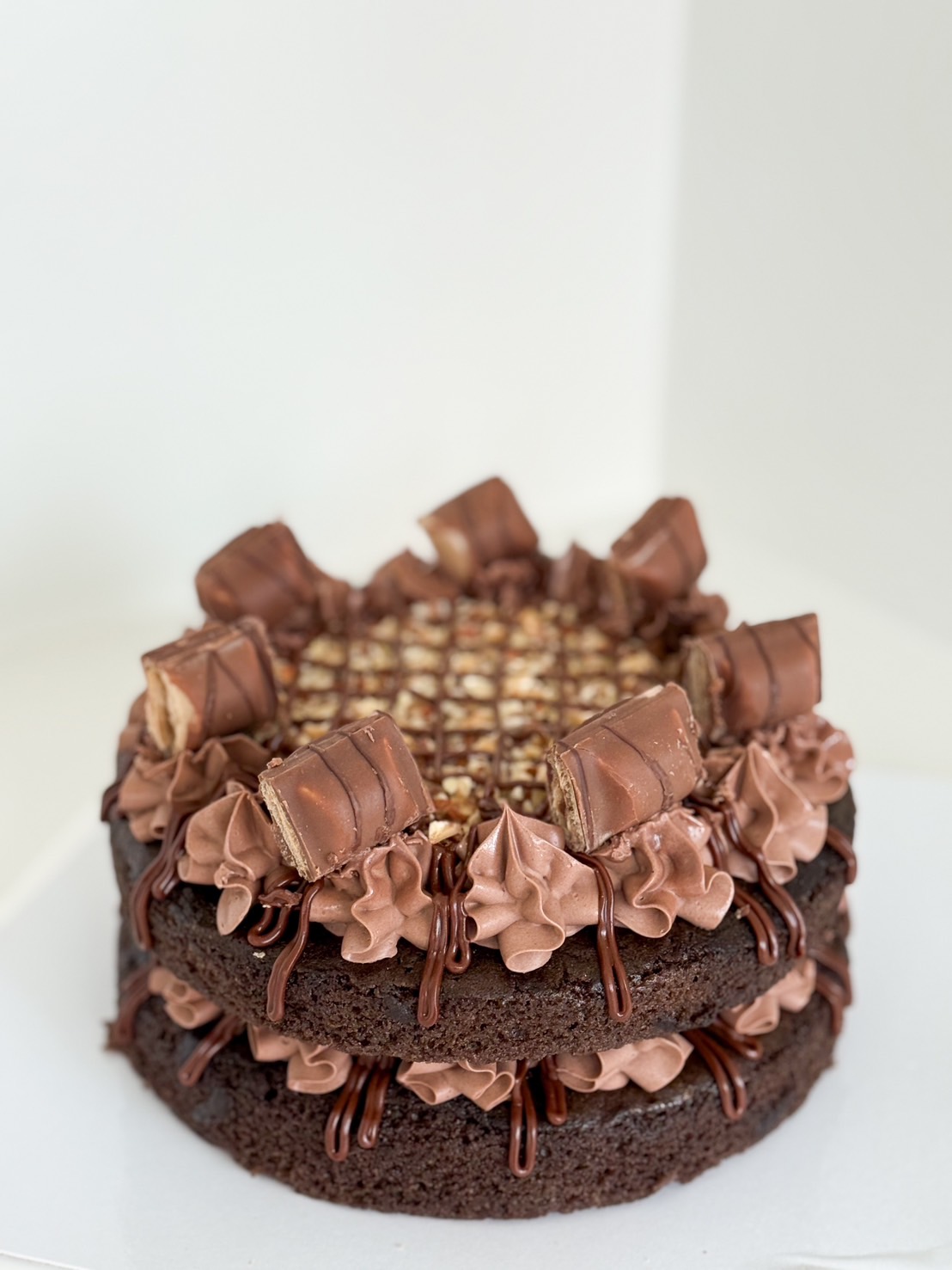 Double chocolate layer cake topped with chocolate buttercream swirls and Kinder chocolate pieces.