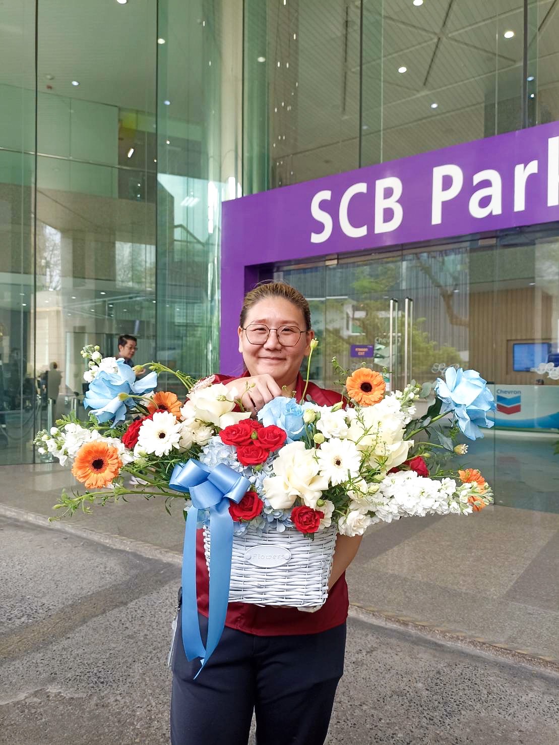 A person stands in front of a building entrance with glass doors and a sign reading 