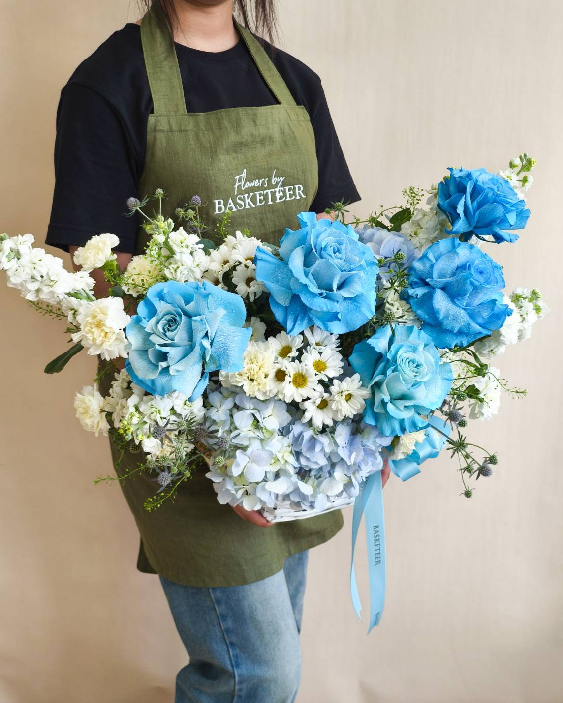 Elegant vase arrangement with vibrant blue roses, soft blue hydrangeas, white stock flowers, and chamomile blooms.