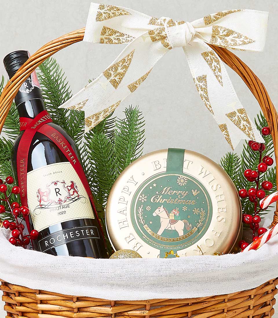 A lavish wicker gift basket brimming with luxurious delights stands before you. At its center, a bottle of exquisite Rochester wine promises indulgence, while a beautifully designed circular tin labeled 