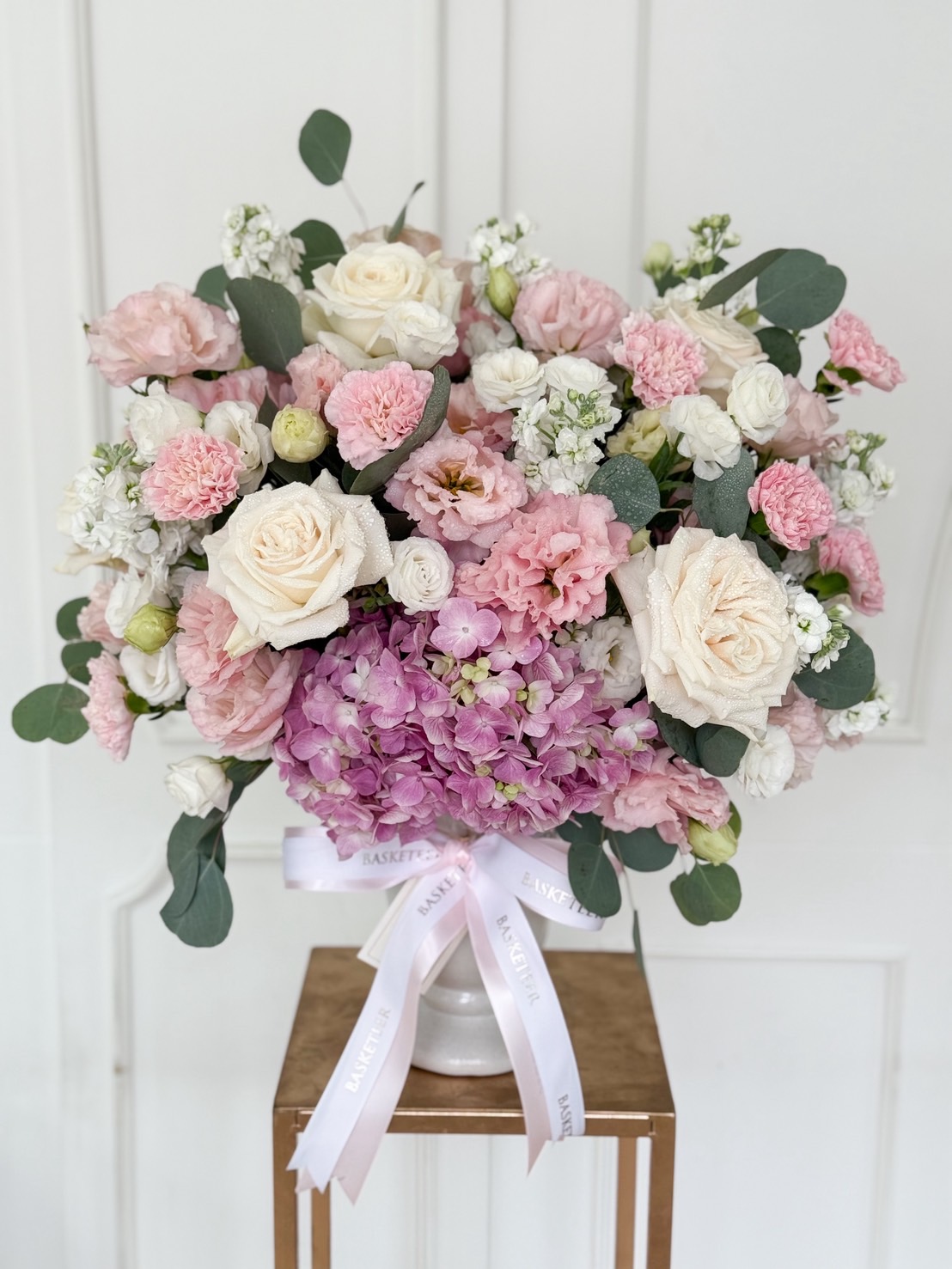 Pastel flower vase arrangement with pink hydrangeas, white roses, pink lisianthus and carnations in a white ceramic vase