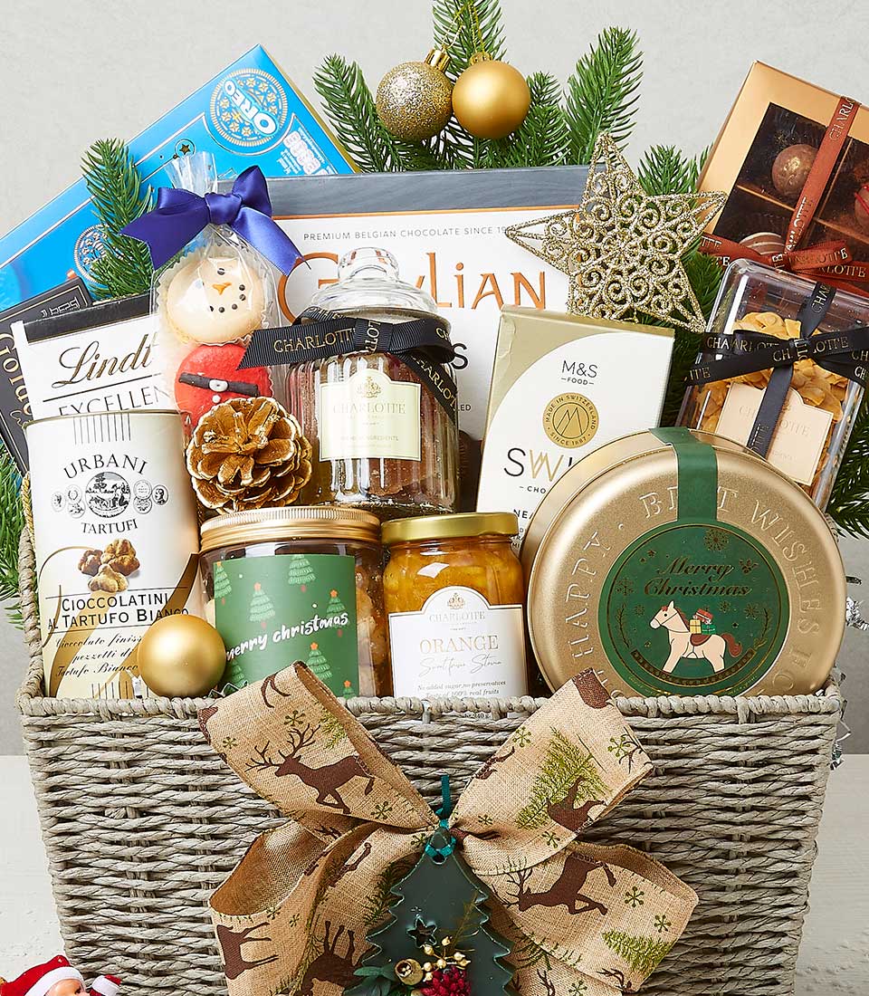 A luxurious wicker basket by Basketeer brimming with an exquisite selection of Christmas-themed delights—decadent chocolates, artisanal cookies, gourmet preserves, and fine teas. The basket is elegantly adorned with lush evergreen sprigs, shimmering gold ornaments, rustic pinecones, and a sparkling star decoration. A charming burlap bow embellished with holly accents graces the front, while delicate ribbons featuring the Basketeer logo add a touch of sophistication to this festive masterpiece.