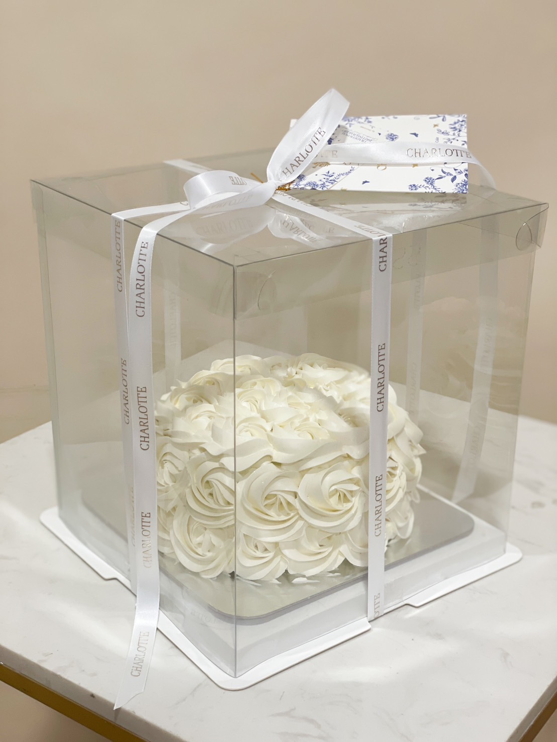 A sophisticated white buttercream cake with delicate rose swirl piping, ideal for weddings, engagements, and elegant celebrations.