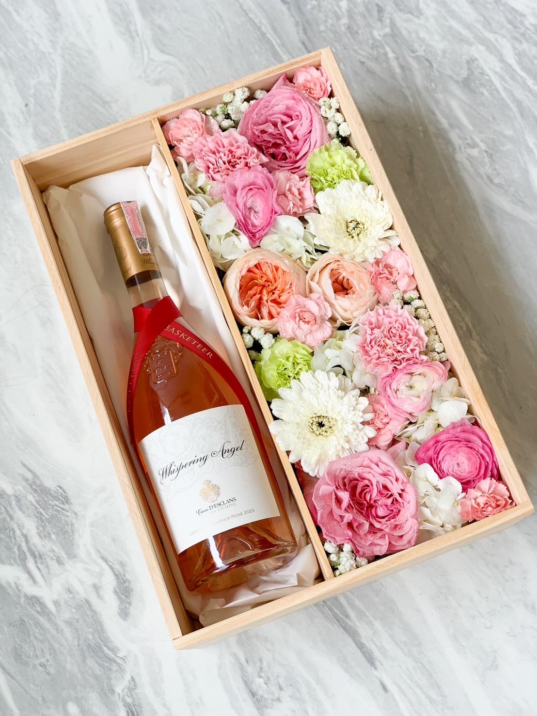 A gift box containing a bottle of rosé wine on the left, labeled 