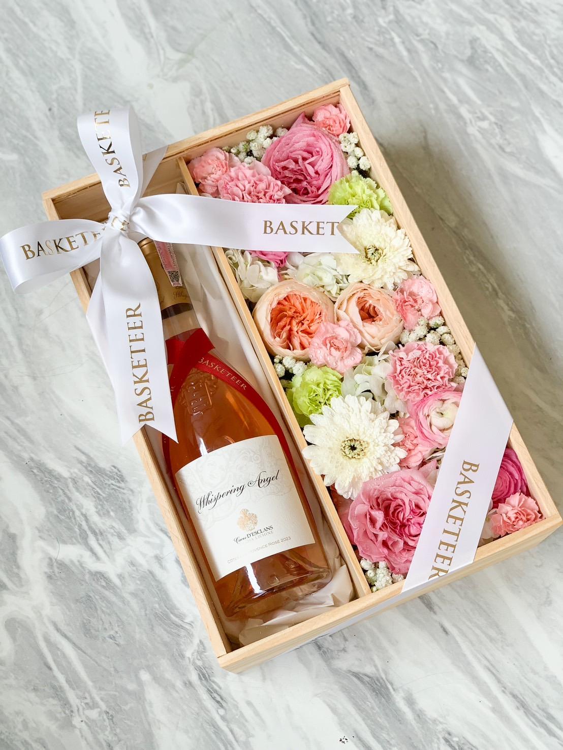 A wooden gift box containing a bottle of rosé wine labeled 
