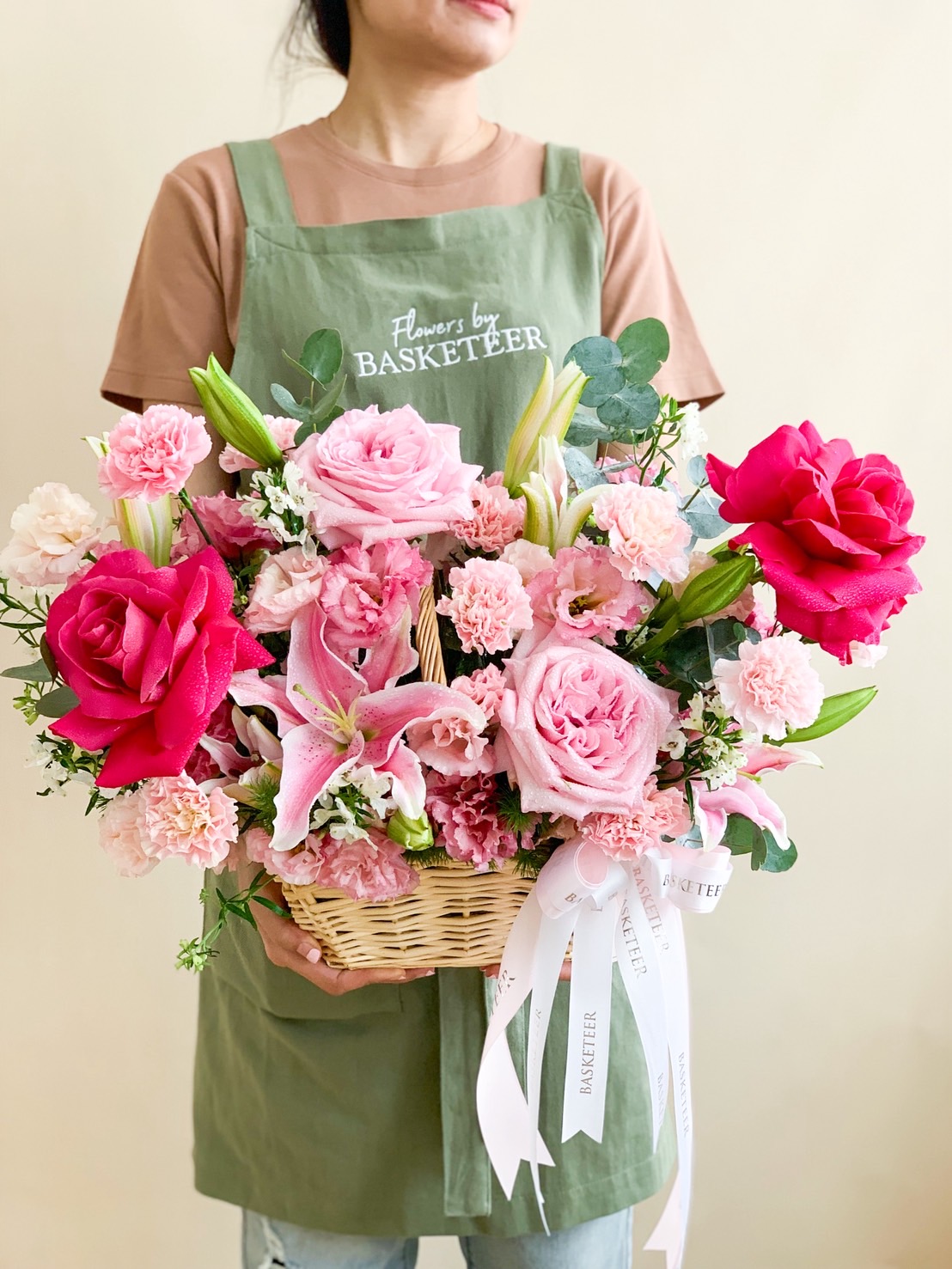 Pink flower basket with roses, lilies, and carnations arranged elegantly in a woven basket.