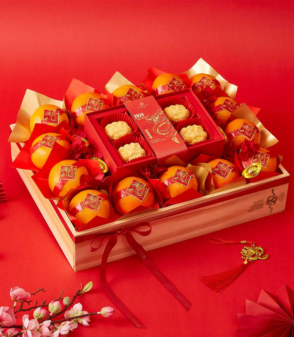 Mandarin oranges and dragon-embossed mooncakes beautifully arranged in a wooden crate with red and gold decorations for Chinese New Year.