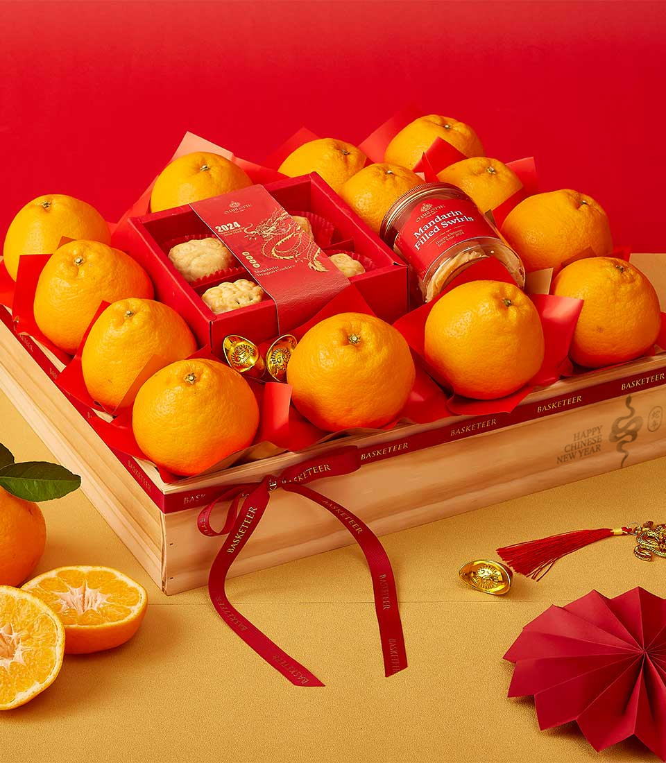 Chinese New Year gift crate featuring mandarin oranges, festive red packaging, cookies, and mandarin-filled sweets in a wooden box.