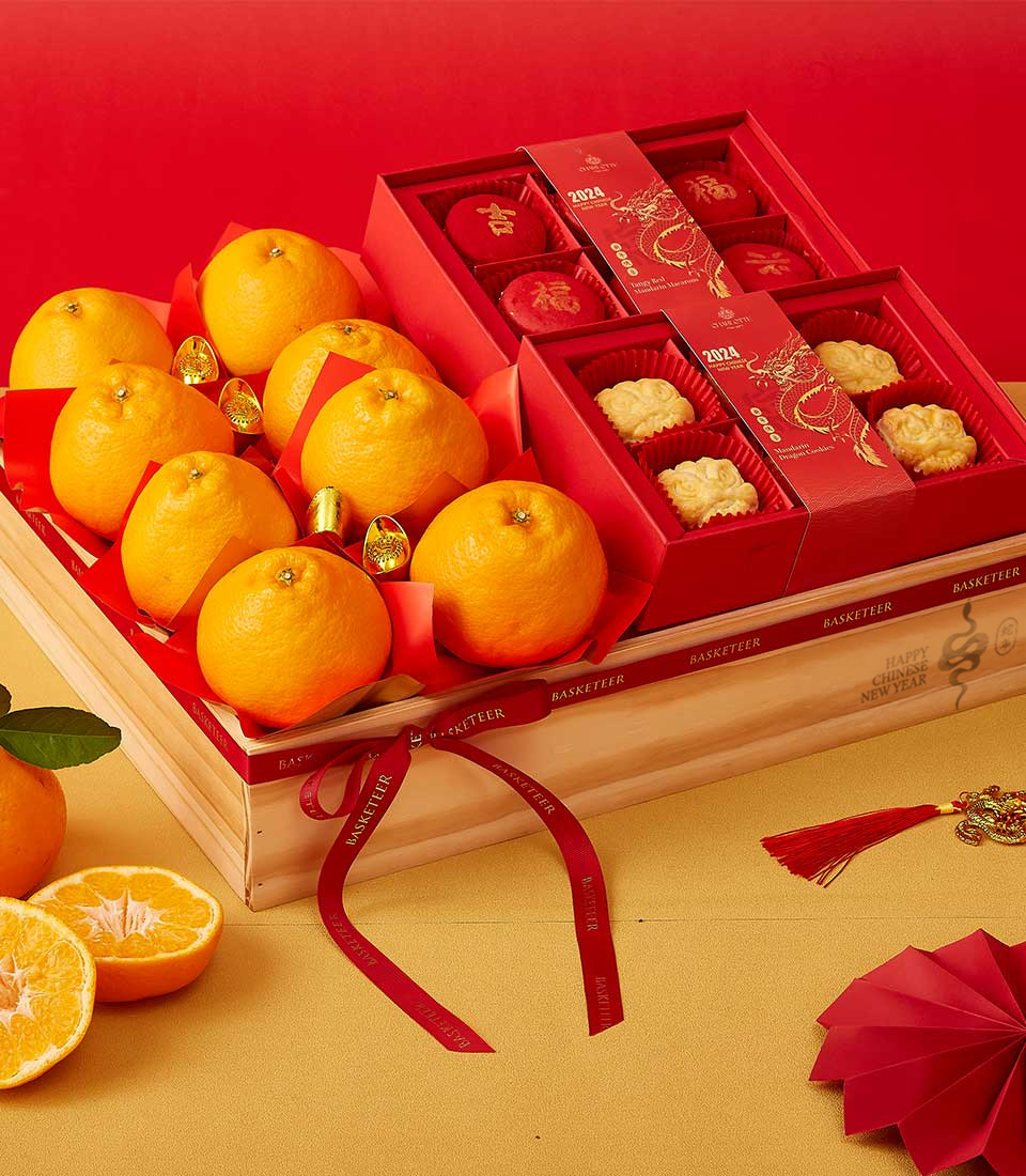 Chinese New Year gift box with vibrant mandarins, mooncakes in red festive boxes, and golden decorations in a wooden crate.