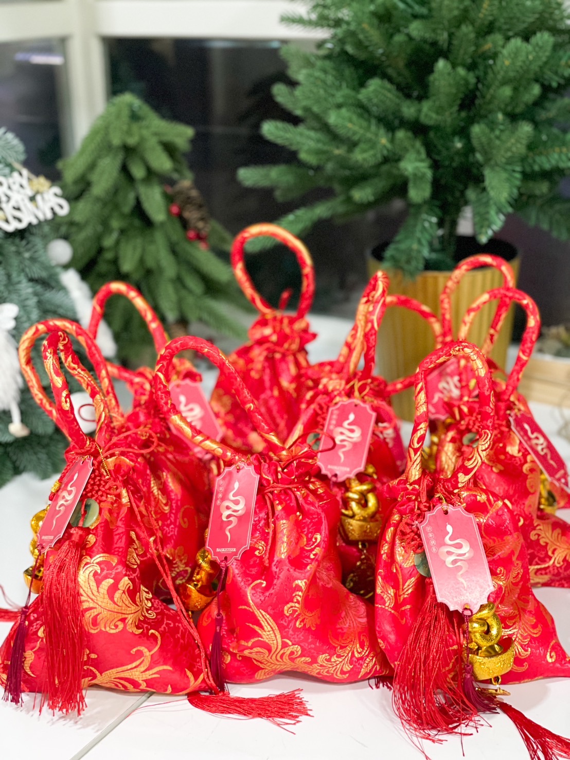 Red satin bag with intricate gold designs, festive tassels, and golden lucky charms, ideal for Chinese New Year gifting.