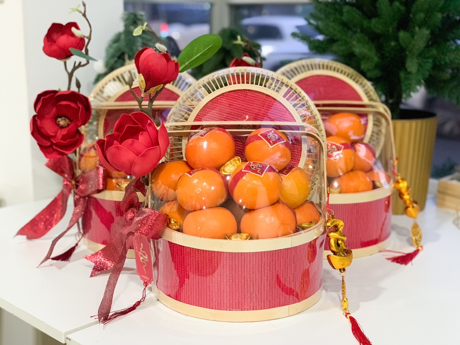 Elegant red basket with fresh mandarins, golden charms, and red floral accents designed for Chinese New Year gifting.