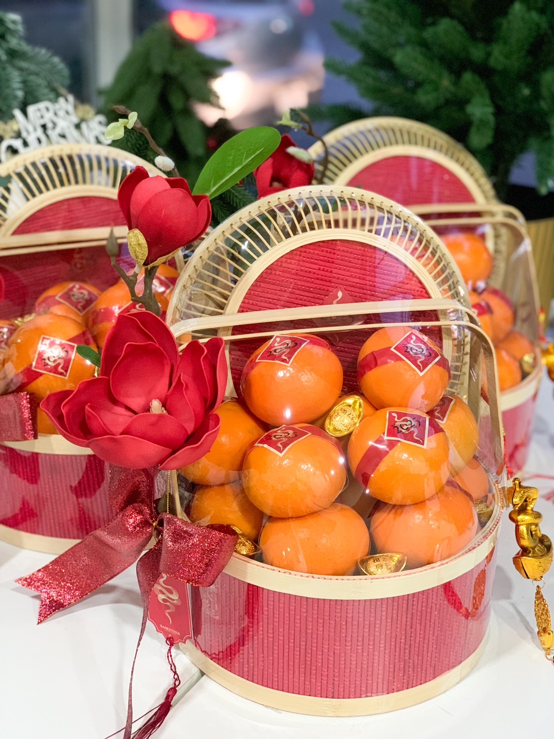 Close-up of a Elegant red basket with fresh mandarins, golden charms, and red floral accents designed for Chinese New Year gifting.