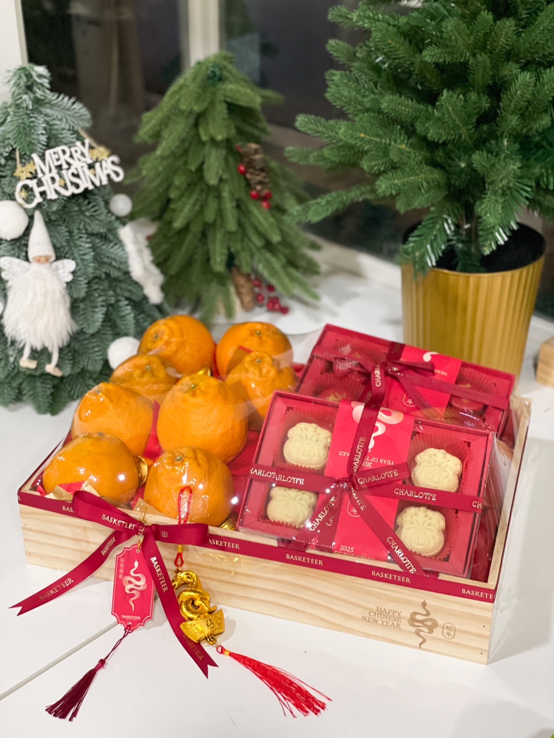 Chinese New Year gift box with vibrant mandarins, mooncakes in red festive boxes, and golden decorations in a wooden crate.