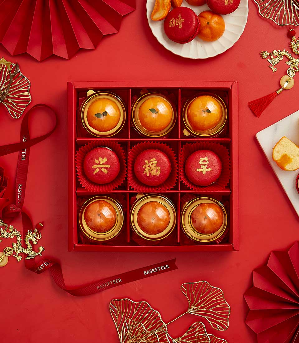 Chinese New Year Sweet Gift In Creamy Mandarin Center Cake, Mandarin Macarons, Salted Egg Cake In The Red Box With a Bow.
