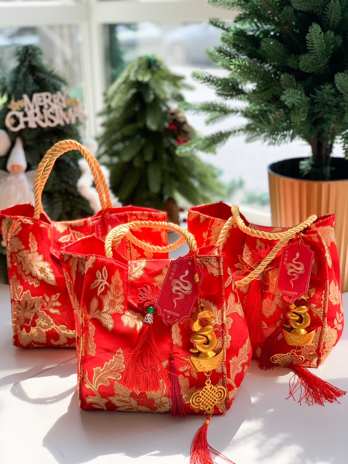 Chinese New Year festive tote bags in red and gold floral brocade, accented with gold rope handles, red tassels, and golden snake charms.