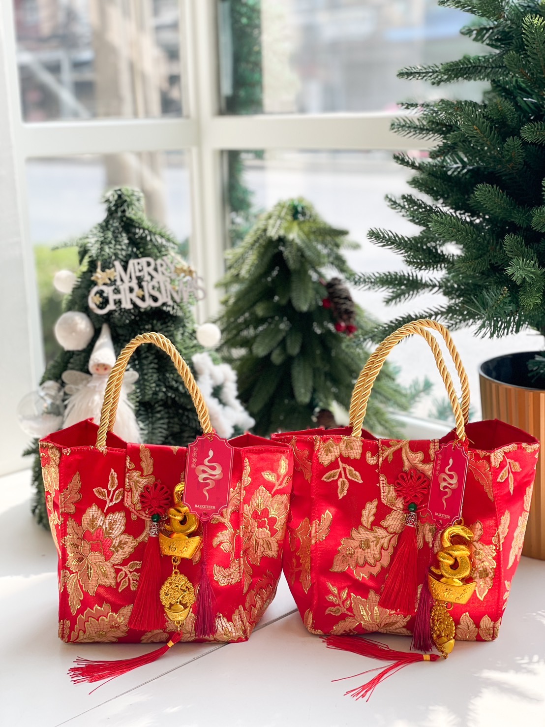 Red brocade tote bags featuring gold floral embroidery, rope handles, and decorative snake charms for Chinese New Year celebrations.
