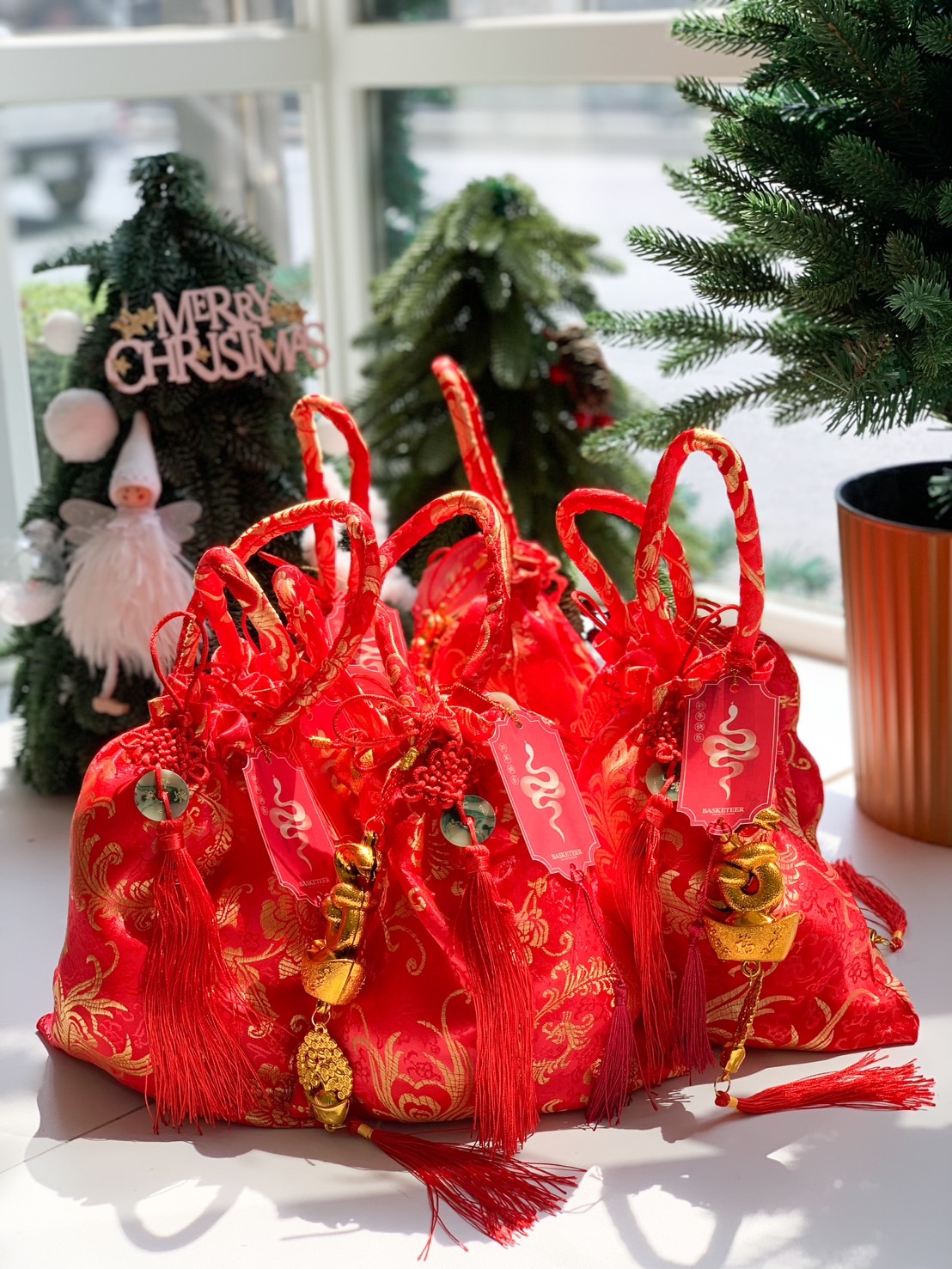 Red satin bag with intricate gold designs, festive tassels, and golden lucky charms, ideal for Chinese New Year gifting.
