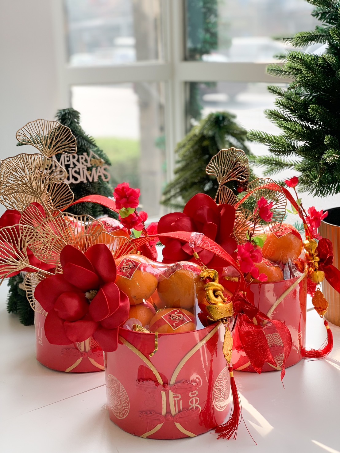 Chinese New Year gift baskets in vibrant red with gold accents, featuring oranges, festive flowers, and golden charms.