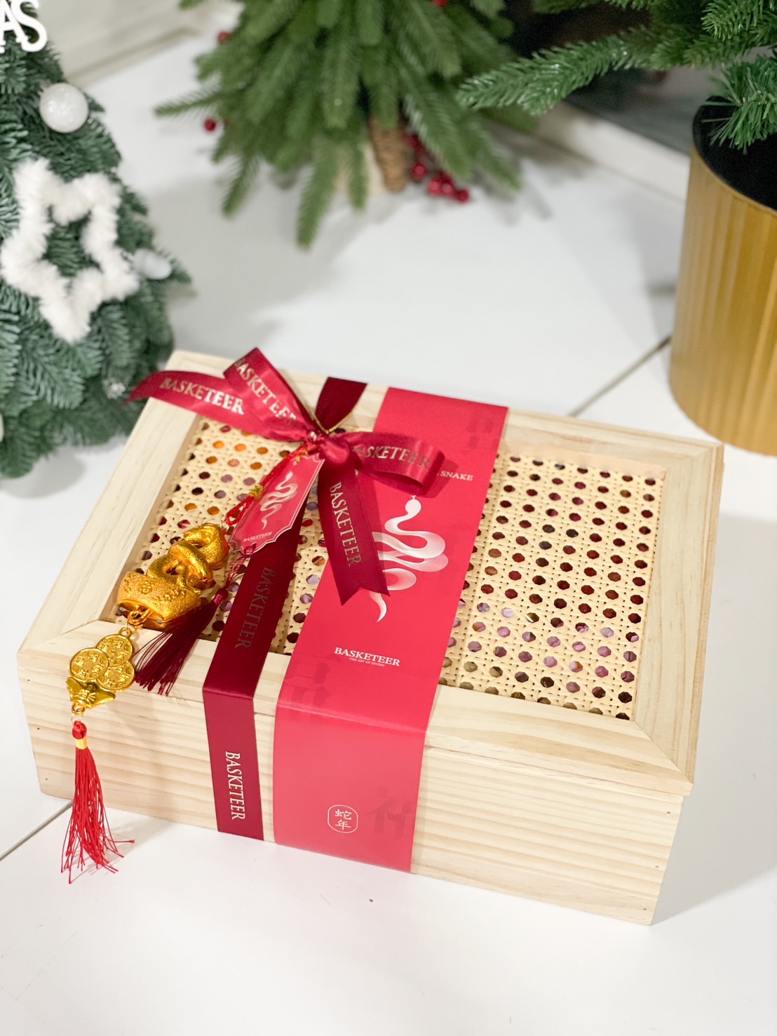 A beautifully crafted bamboo box with red ribbon, golden snake charm, and a festive Chinese New Year design.