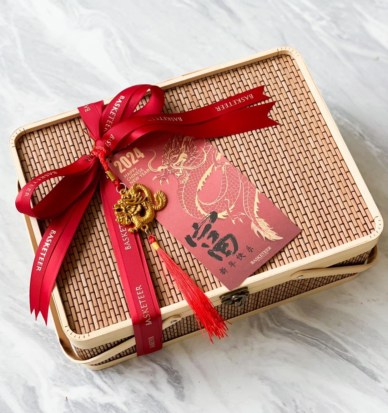 A rectangular woven box is tied with a red ribbon embossed with 