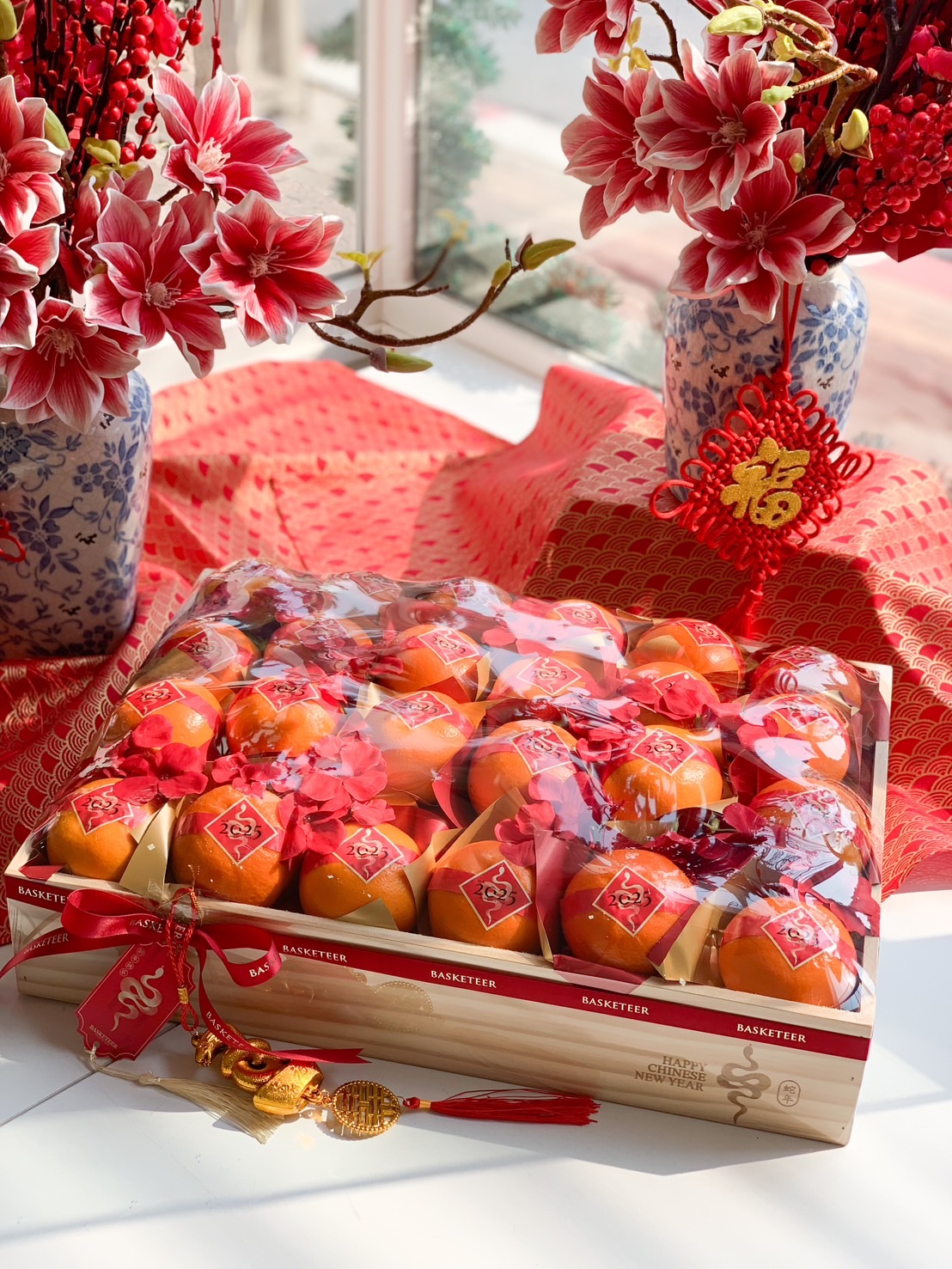 Luxury Chinese New Year gift box filled with premium mandarin oranges, decorated with festive red ribbons, golden accents, and traditional motifs.