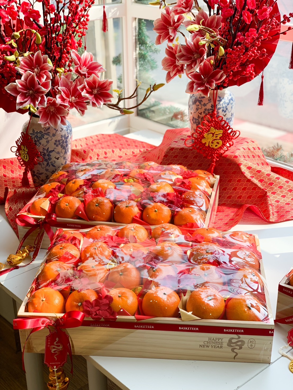 Chinese New Year gift box filled with fresh mandarin oranges, wrapped in festive decorations and a wooden box for a luxurious presentation.